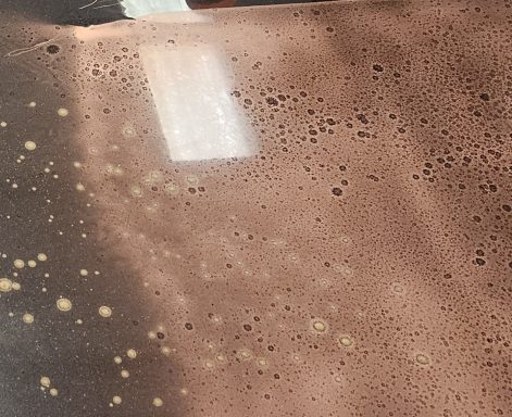 Brown liquid with bubbles and reflections, creating a textured surface.