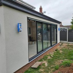 Modern extension with large glass doors, light walls, and a landscaped garden area. Silicone thincoat in chalk white in area of redditch