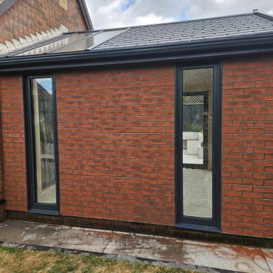 Exterior view of a brick extension with large black-framed windows.