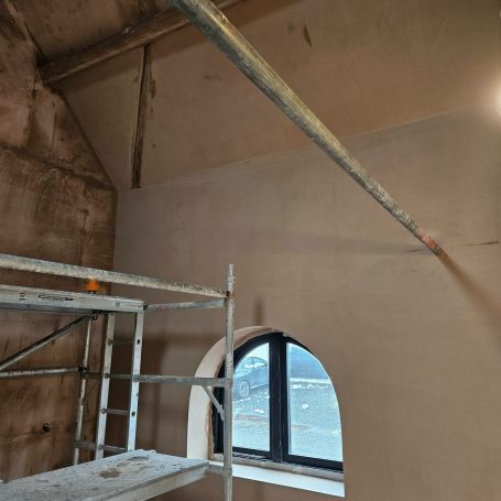 Scaffold next to a wall with a window and a pipe running across the ceiling. Plastered in gypsum by fis finishes in ombersley